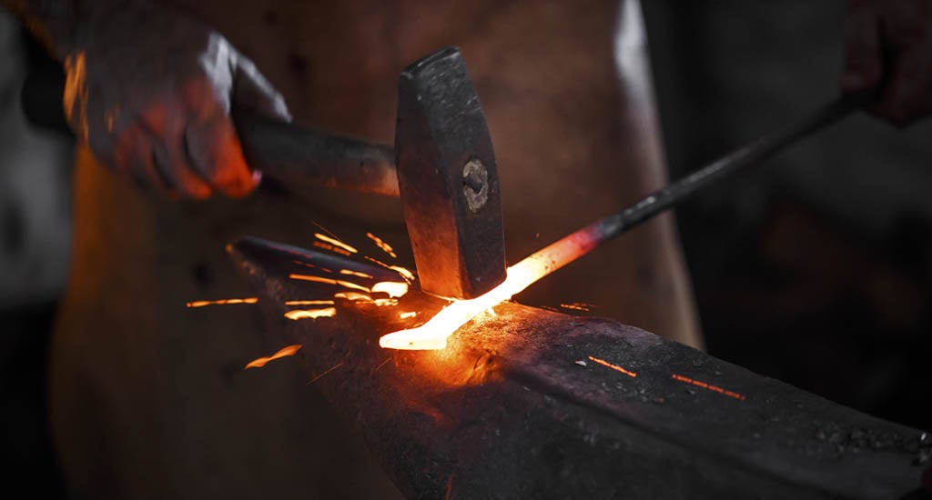 Blacksmith forging molten metal on an anvil