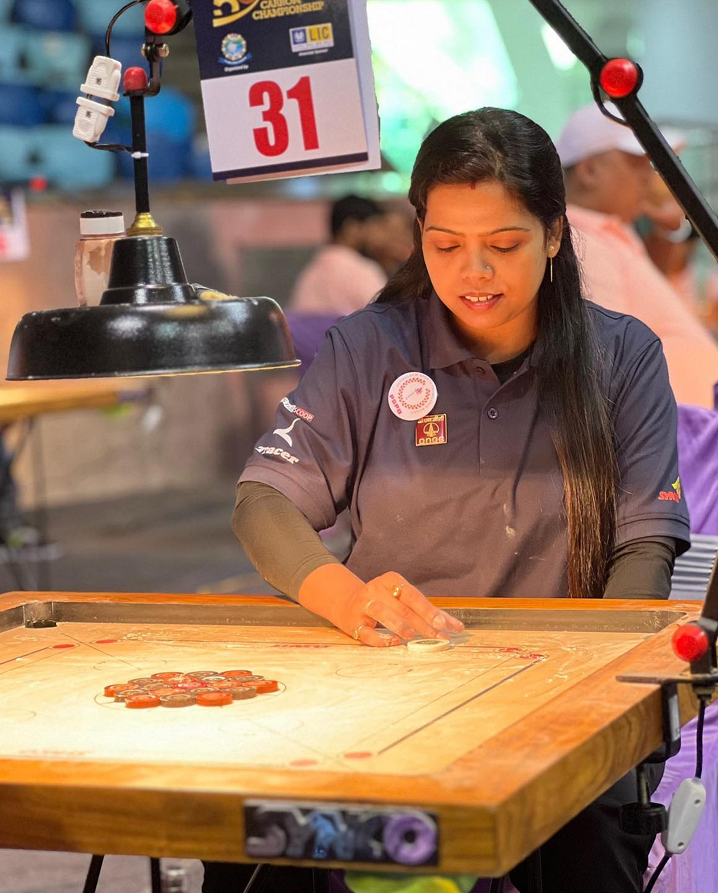 Rashmi Kumari sitting in front of the carrom is about to make her move