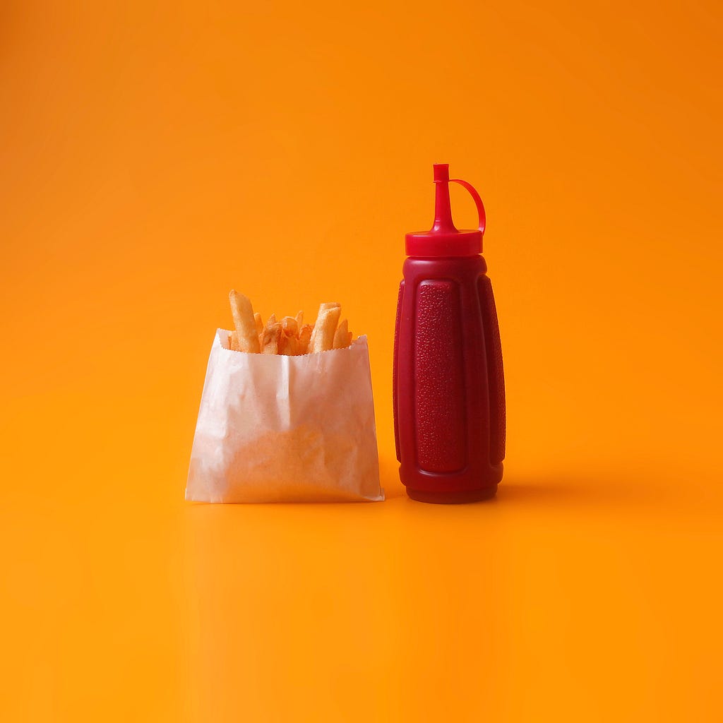 A packet of French fries and a bottle of ketchup