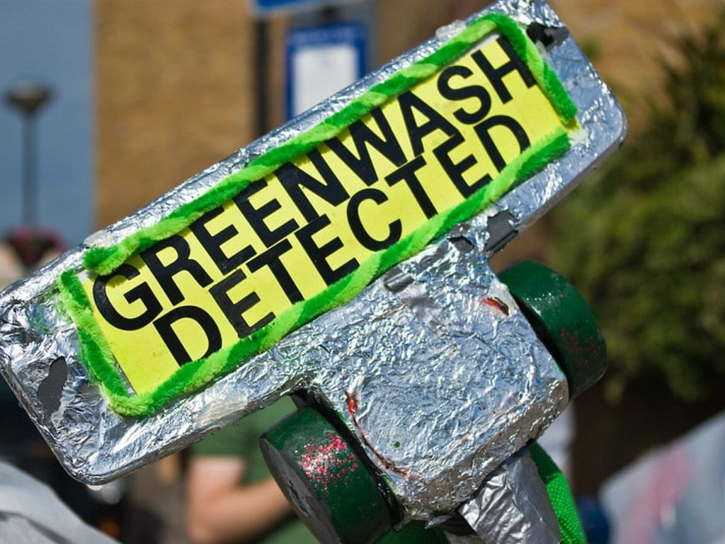 A silver-colored sign says, greenwash detected