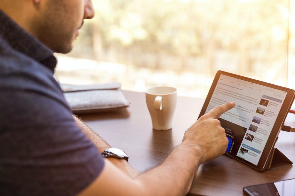 An agent or employee taps on a touch screen with a cup of coffee on the table