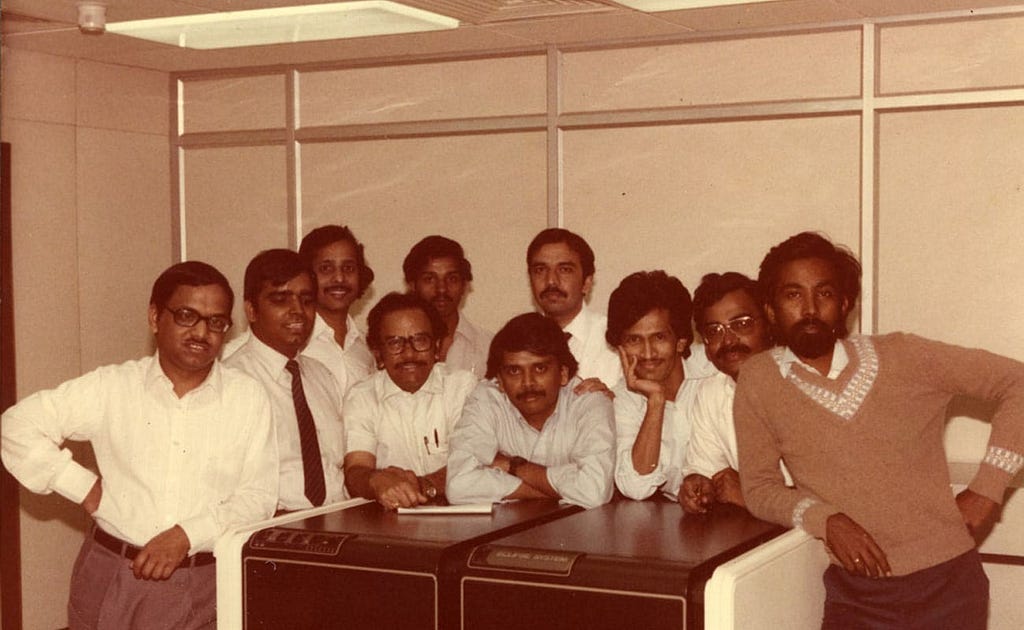 Group of employees standing on a desk for a photograph, old photo around 90s