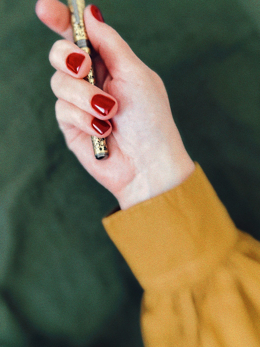 A right hand with a yellow sleeve is holding a pen