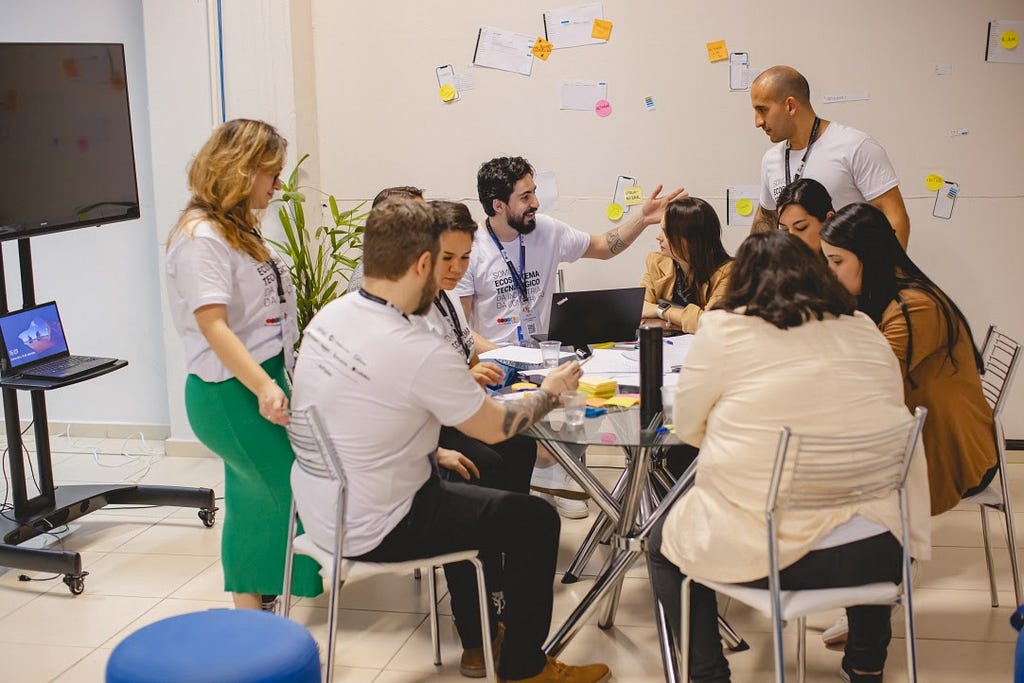 Workshop presencial com clientes e designers na mesa colaborando