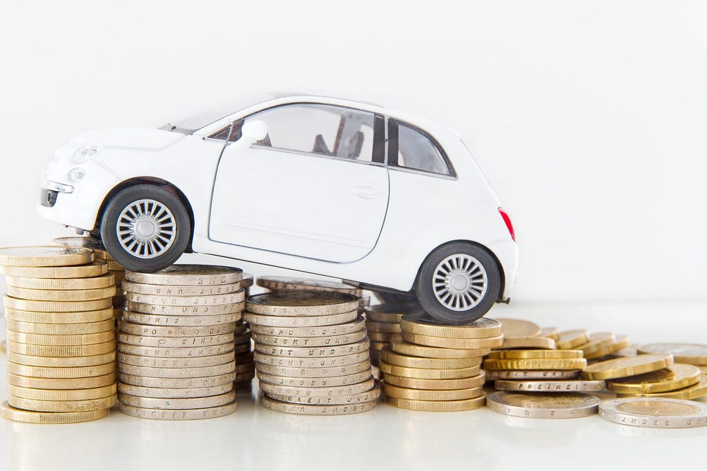 A miniature car over coins of money depicting the hefty cost of parking