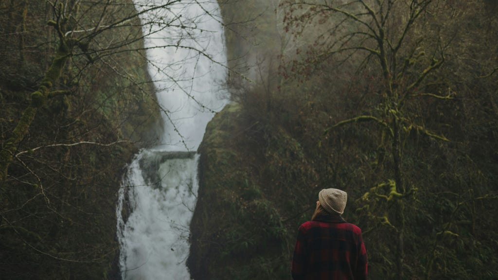 A solo traveler looking at a waterfall