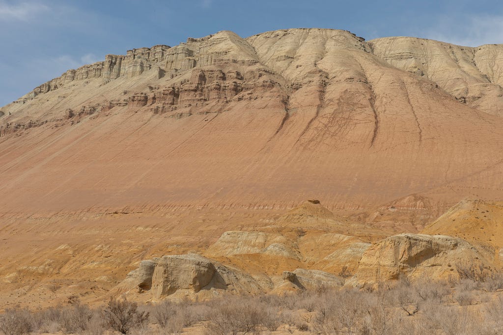 Photograph of eroded rocks with new sedimentary layers forming downstream.