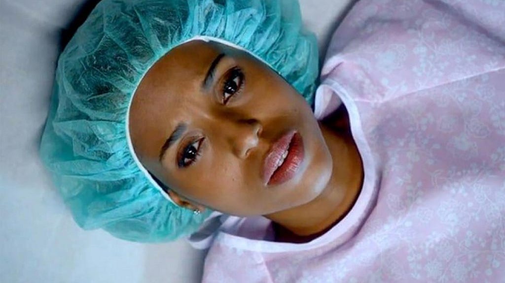 A Black women lies on an operating table. Image is a closeup of her face.