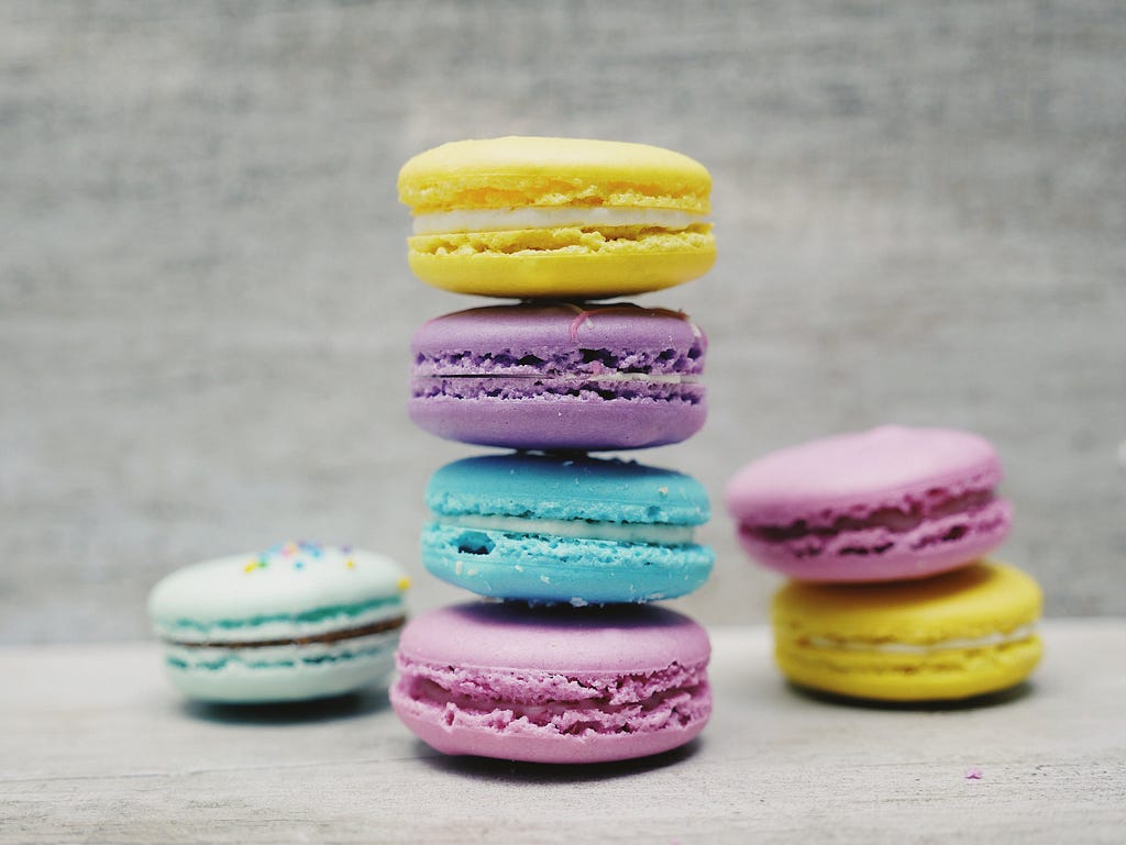 A stack of yellow, purple, blue and pink macaroons