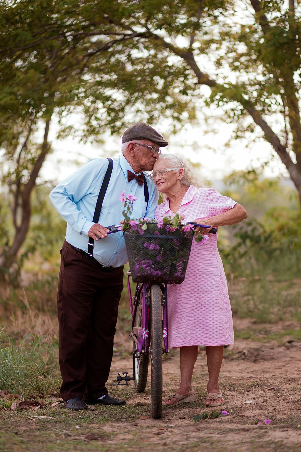 A man kissing his elderly wife on the head as they interrupted their ride