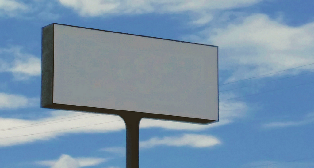 an empty billboard, behind it blue sky with white cloud