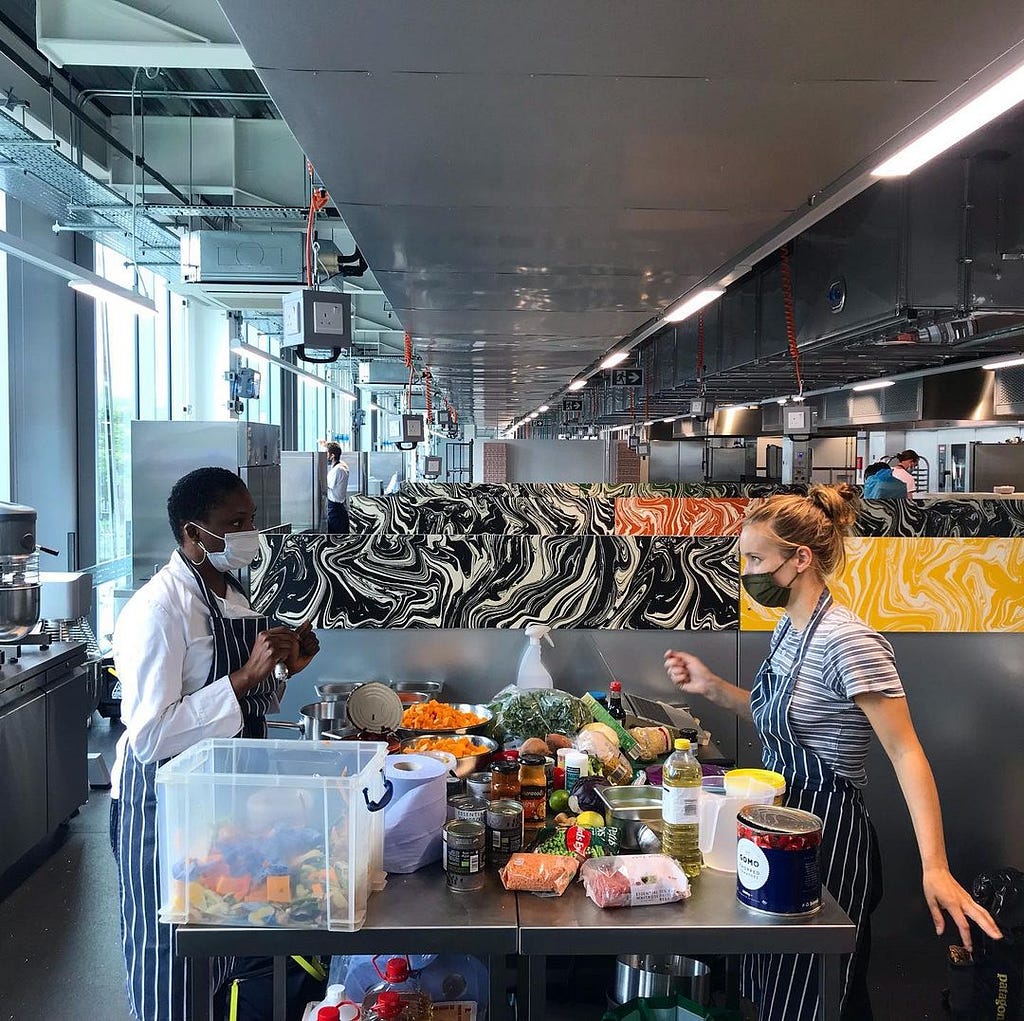 Two people preparing food in a community kitchen