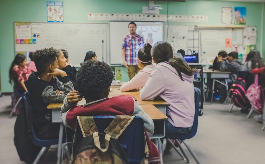 Students in a classroom, with the teacher up front