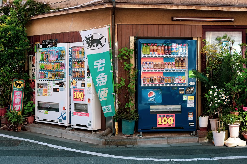 3 vending machines on a street corner in Tokyo.