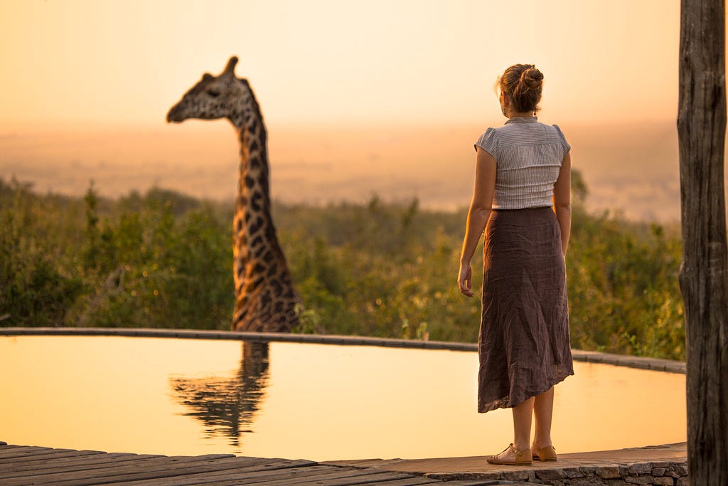 Woman in a nature reserve looking at a giraffe.