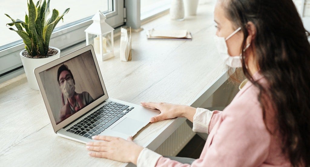 Two people having a video chat and wearing surgical masks