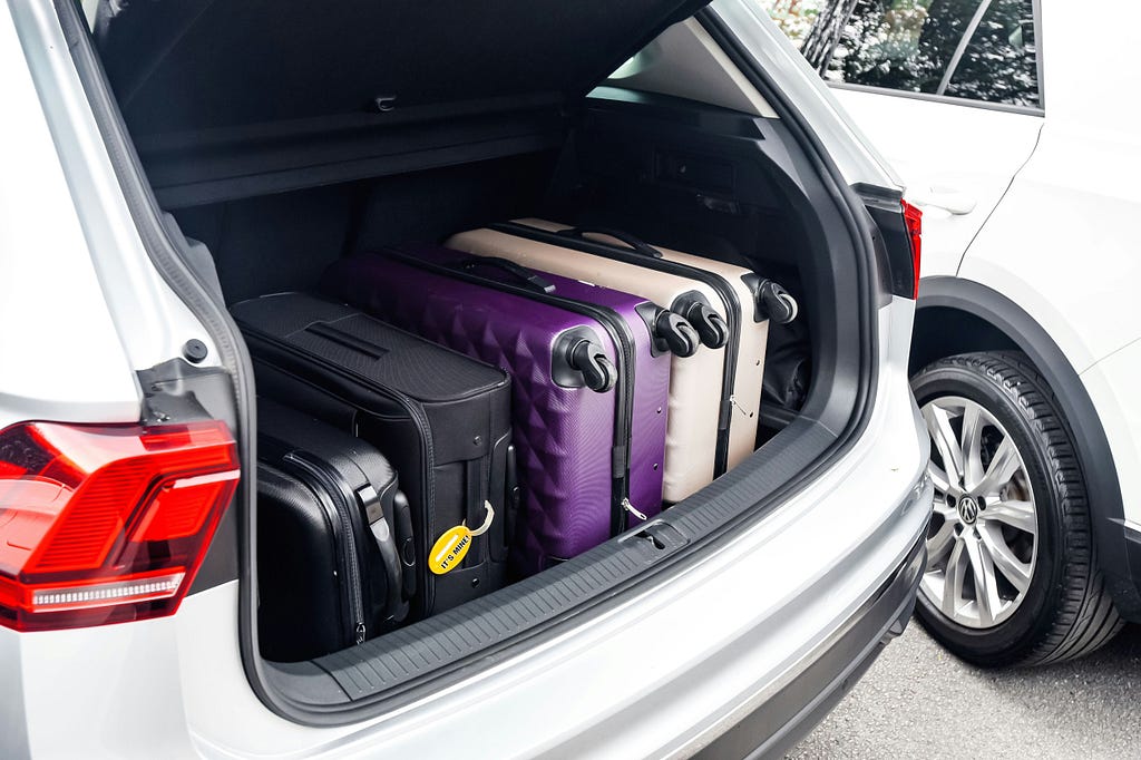 An open trunk of a car with luggage inside.