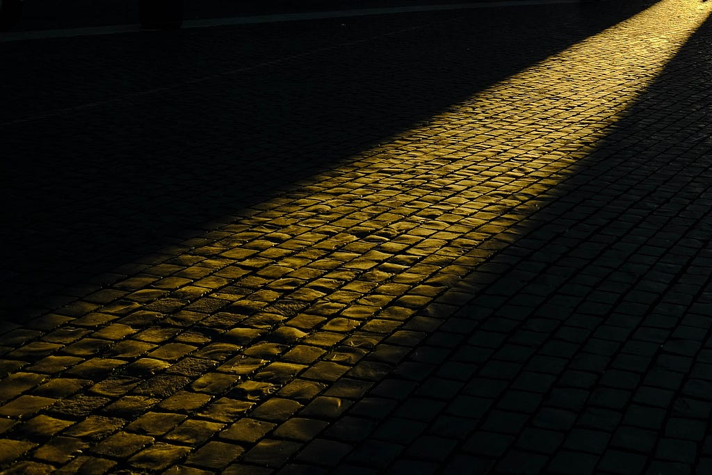 Path of light on cobblestone road.