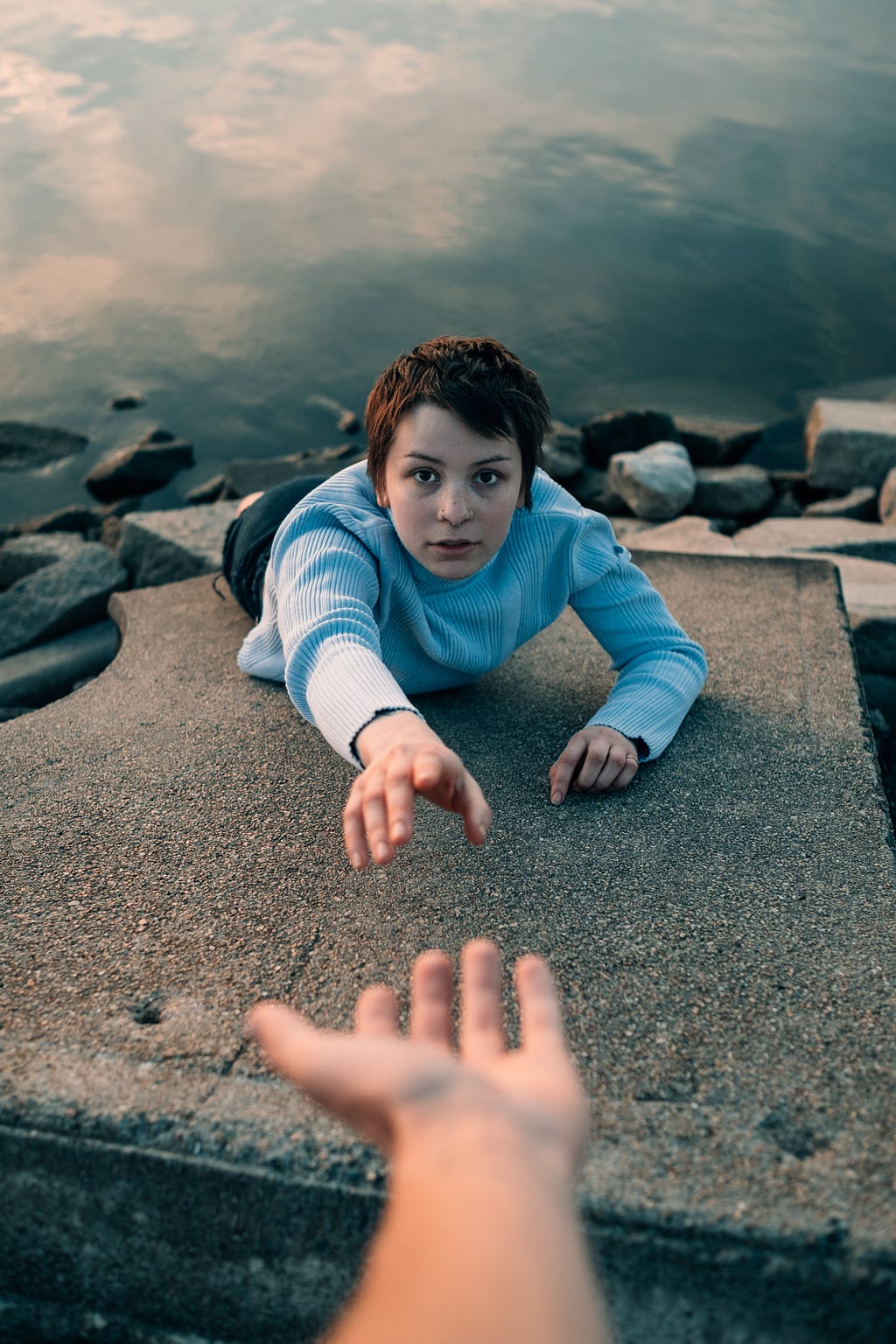 Girl falling into water with hand reaching out for help.