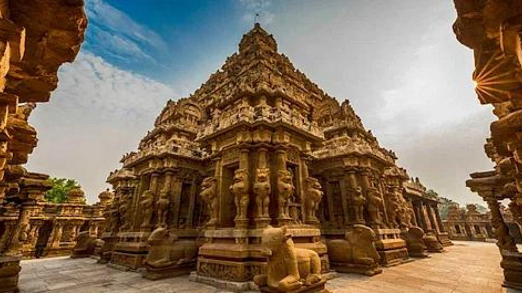 A magnificent ancient temple with intricate carvings and tiered architecture, likely from South India. The structure is adorned with ornate sculptures and lion-like guardian figures, with a stone Nandi statue in the foreground. The temple’s rich detailing and grand design reflect Dravidian architectural style.