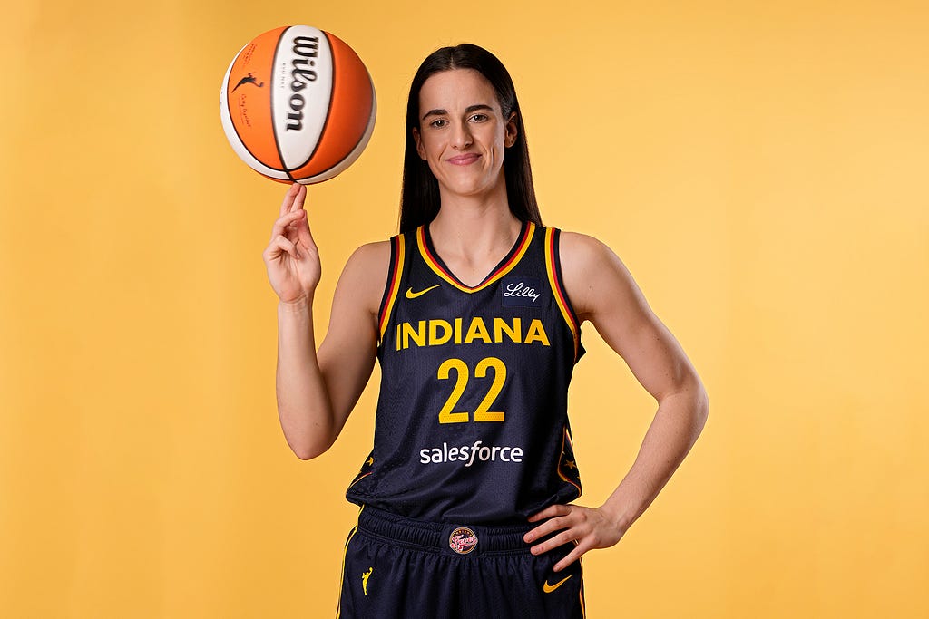 Caitlin Clark with hair down wearing Black Indiana Fever jersey twirling basketball on yellow background