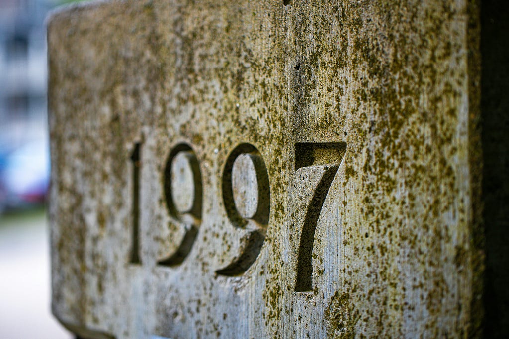 The numbers 1997 chiseled into a stone plaque covered with moss and lichen