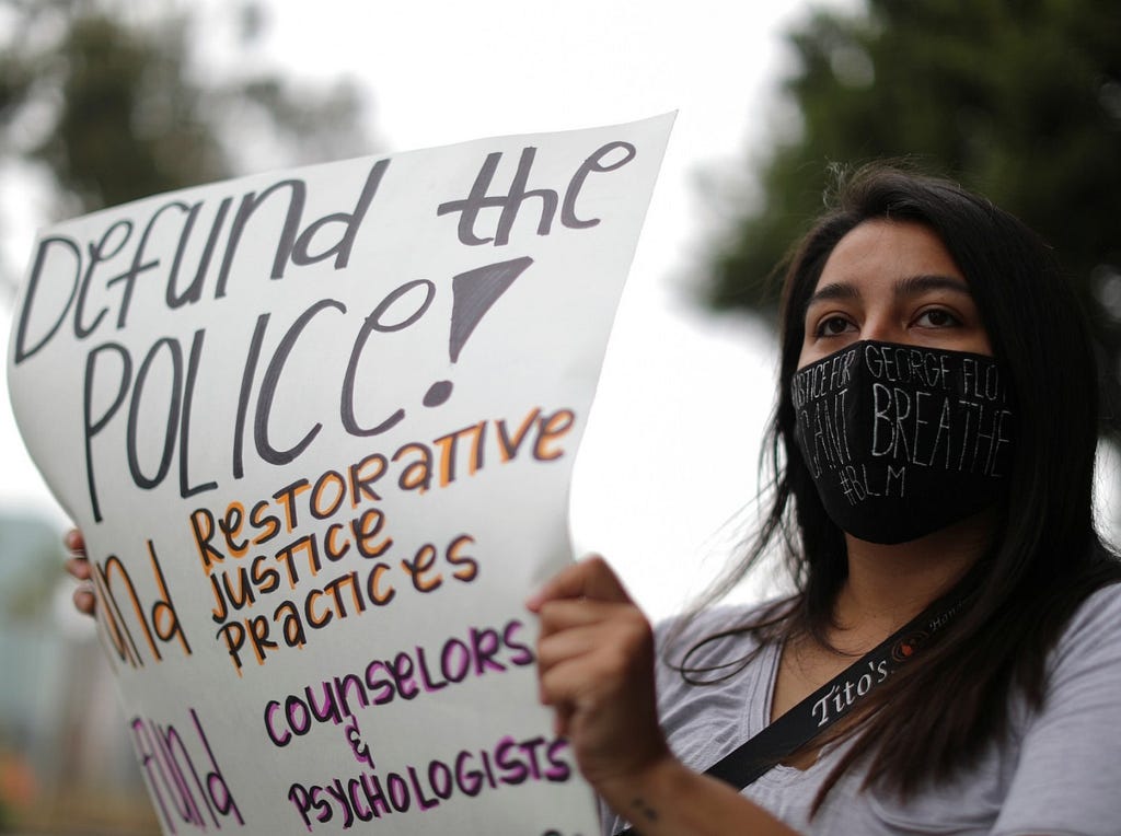 Woman in mask holding a sign at a Los Angeles protest, June 23, 2020. Photo by Lucy Nicholson/Reuters