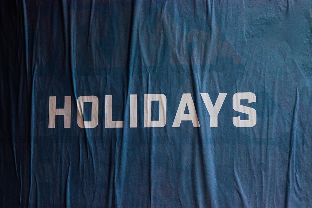 A blue cloth banner with white letters that says: Holidays.
