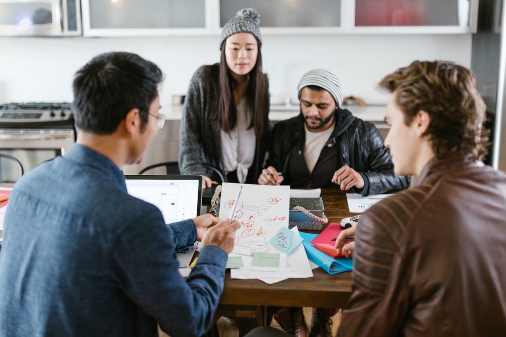 team of three men and a lady discussing a report