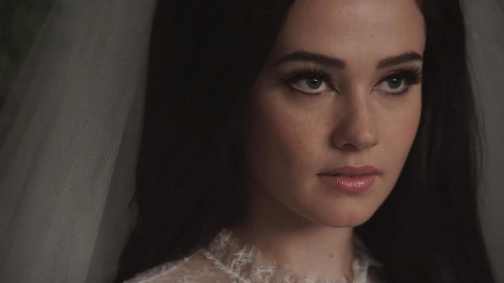 Cailee Spaeny is pictured in wedding attire from the film Priscilla. She has her signature eyeliner makeup in the picture.