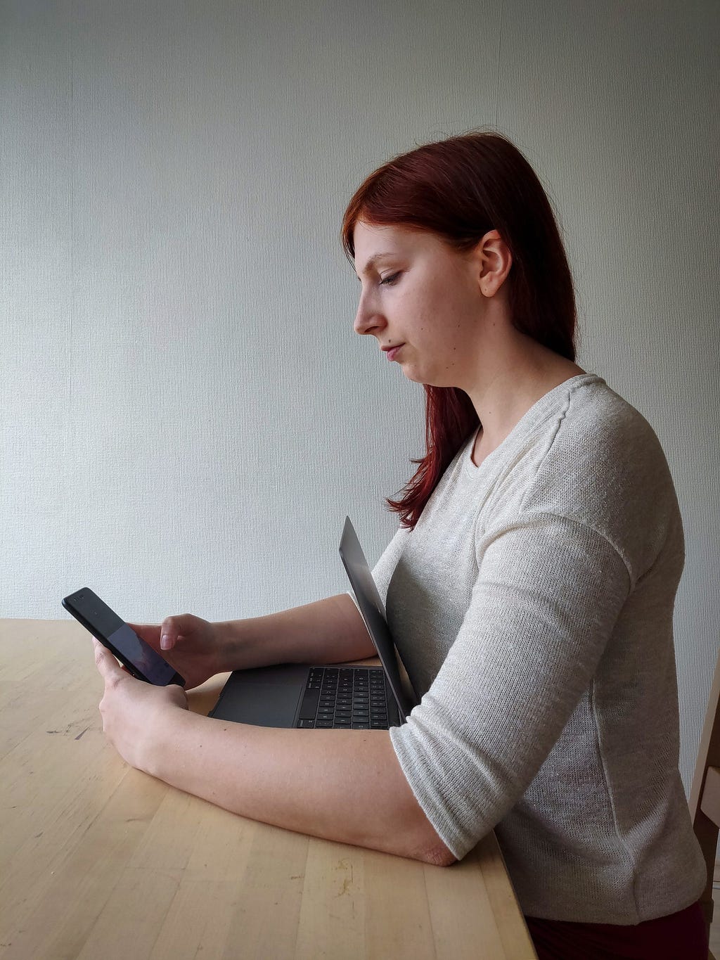 Woman hugging her laptop while using her mobile device