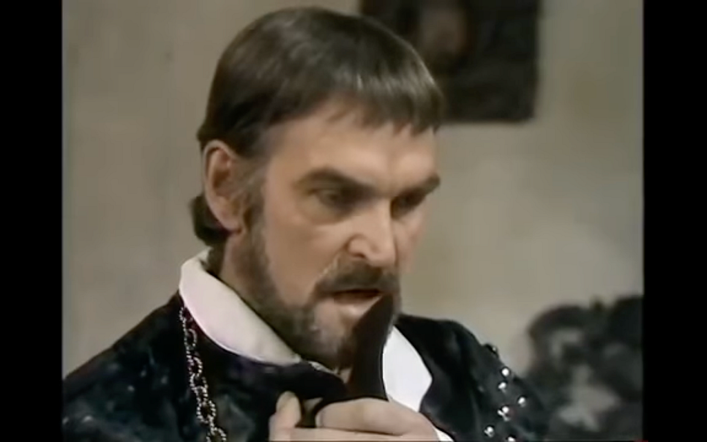 Stanley Baker plays De Flores in BBC’s 1976 production of “The Changeling” . He is depicted staring off while clutching a black glove to his chest.