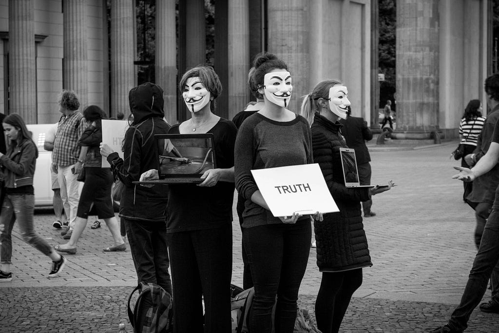 People with masks of anonymity in a circle on a busy street