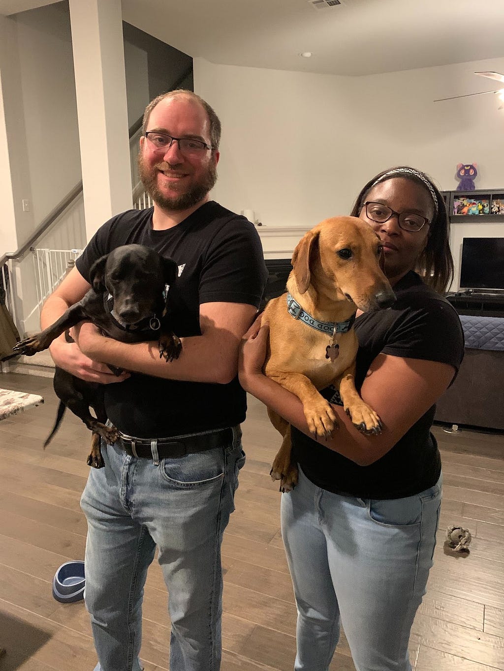 Jessica and her husband standing in their home, each holding an adorable dog!