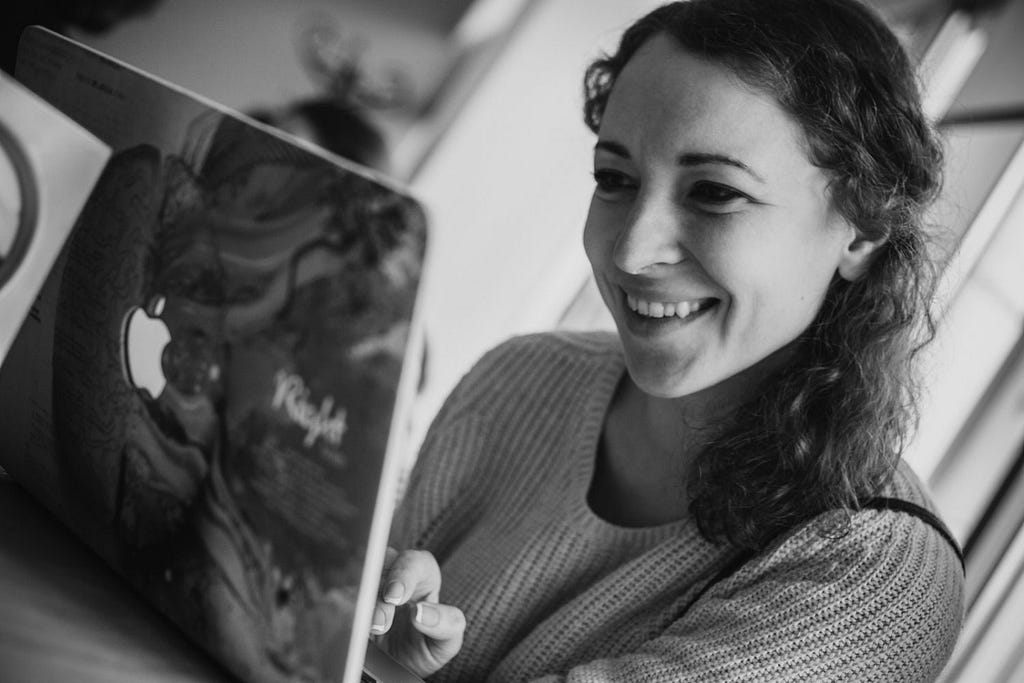 Candid photo of Tetiana Herasymova smiling and working on her laptop.