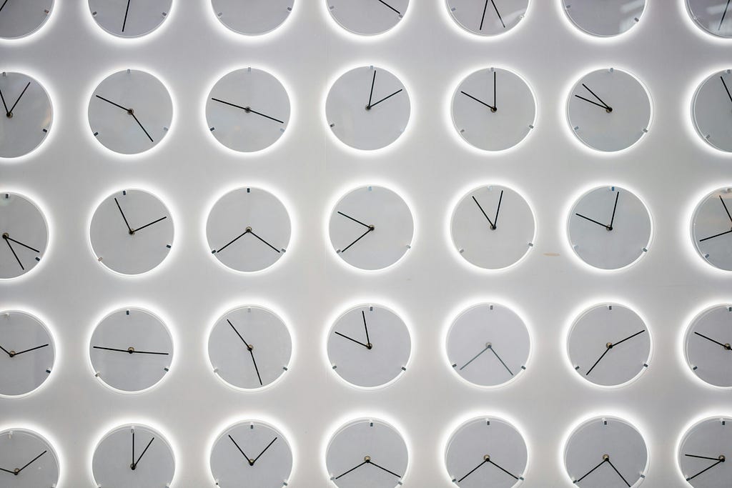 A plethora of clocks running left to right and up and down, pointing to different times by Donald Wu