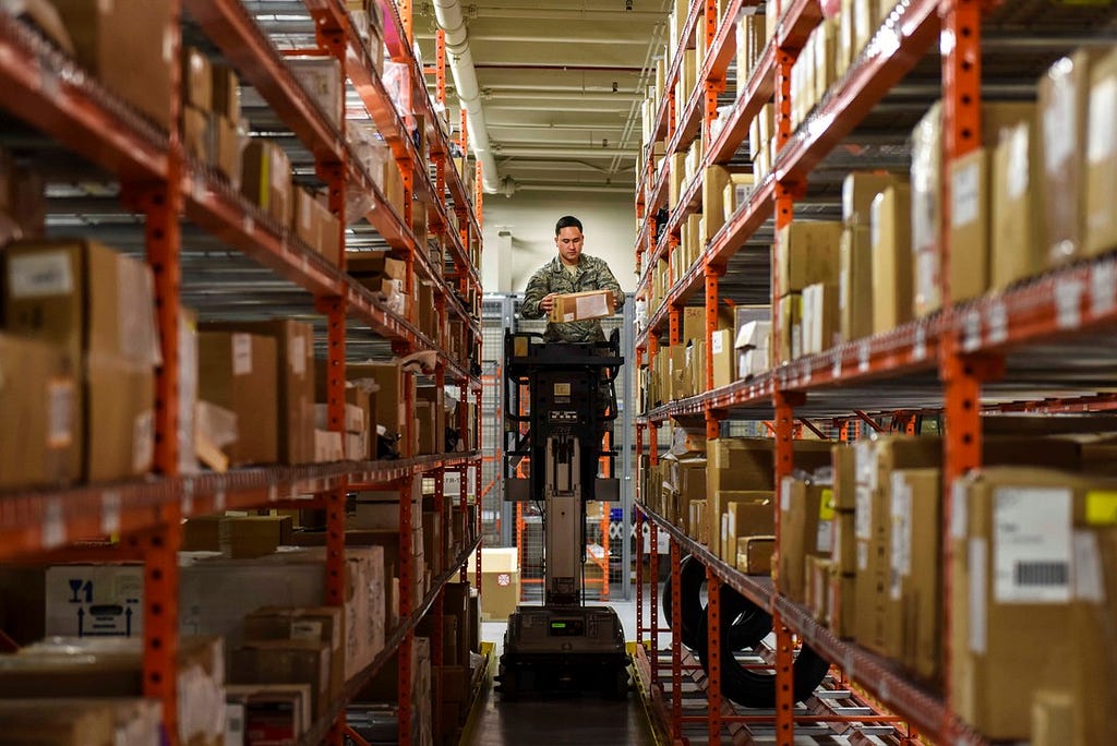 Man surrounded by shelves full of boxes in distribution warehouse
