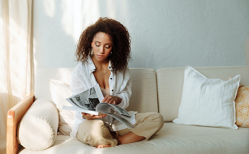 Image of a woman reading a book while sitting on the couch
