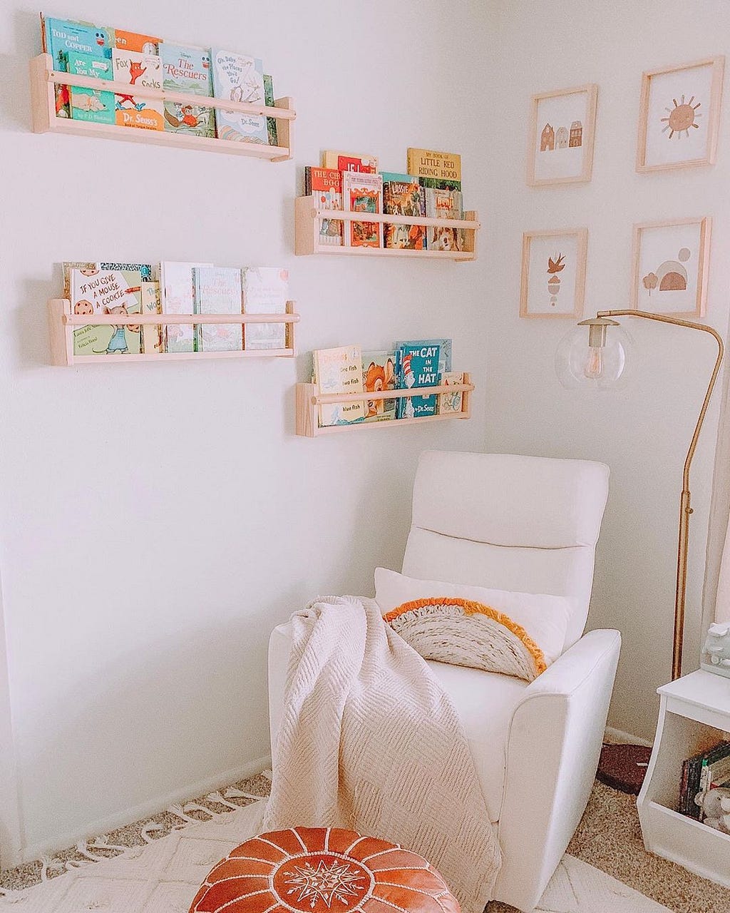 A kids room reading corner with a white reclining seat and wood framed wall art with wood shelves with books on the wall.