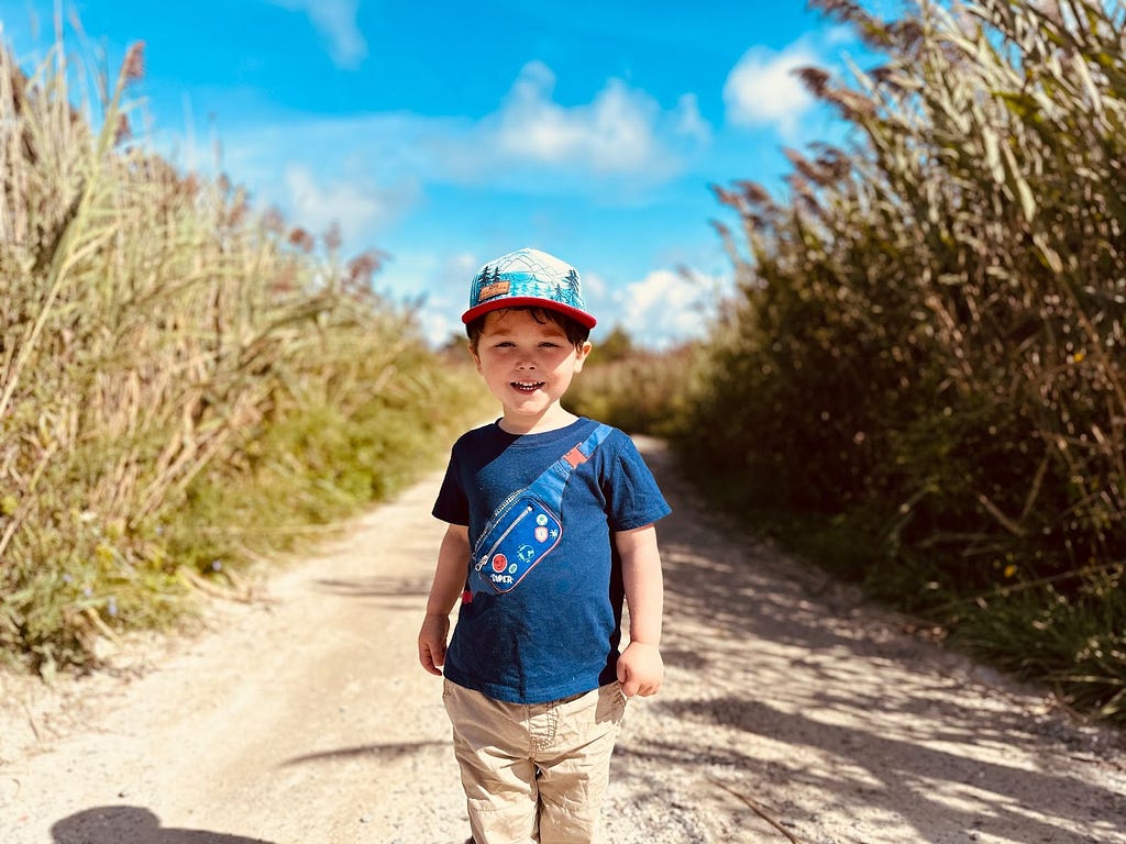Small boy smiling outside on a farm in the sunshine