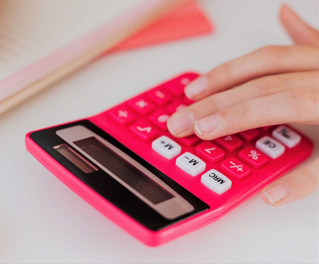Fingers over a pink calculator