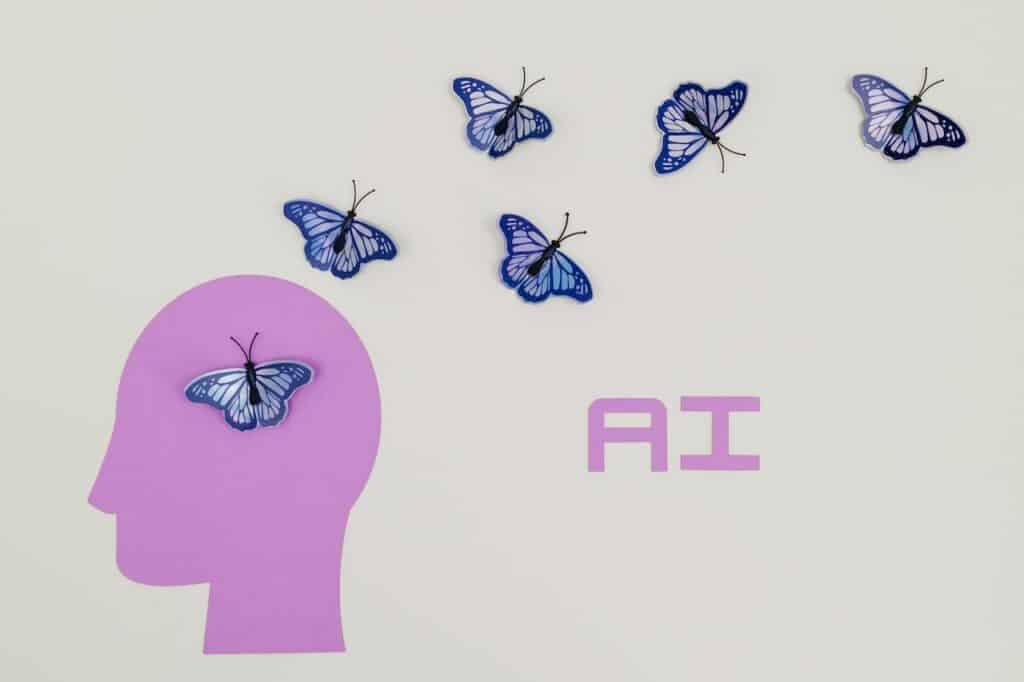 A picture of a purple human head, with butterflies flying out and the word “AI” written. This represents a person upskilling themself in AI