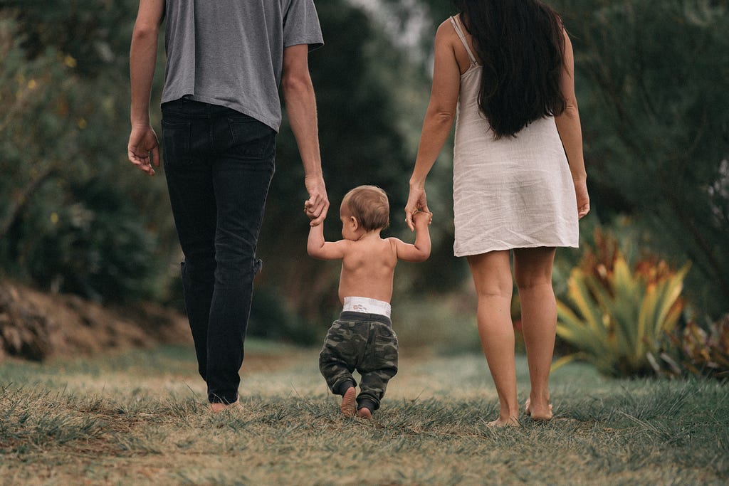 Parents walking with baby on a hiking trail.