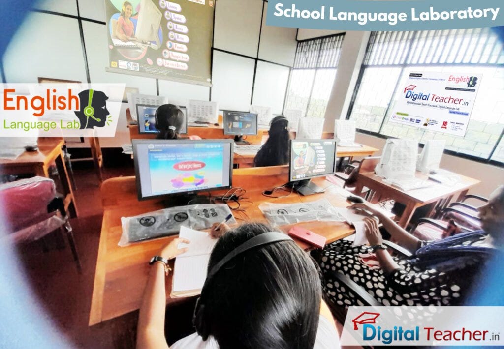 Students sit at computer equipment in an English language laboratory, with a large screen showing the ‘English Language Lab’ and a teacher nearby.