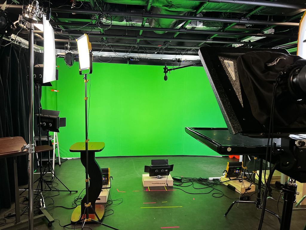 A filming studio with a green screen and video equipment