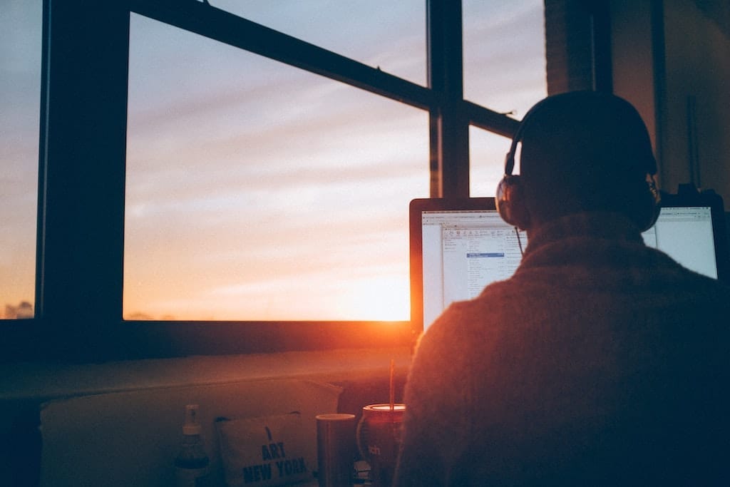 Photo via unsplash of a person working at a computer with headphones on, intended to represent working and videoconferencing