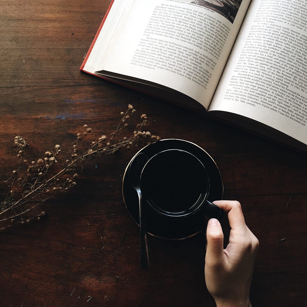 Hand with coffee cup, and open book