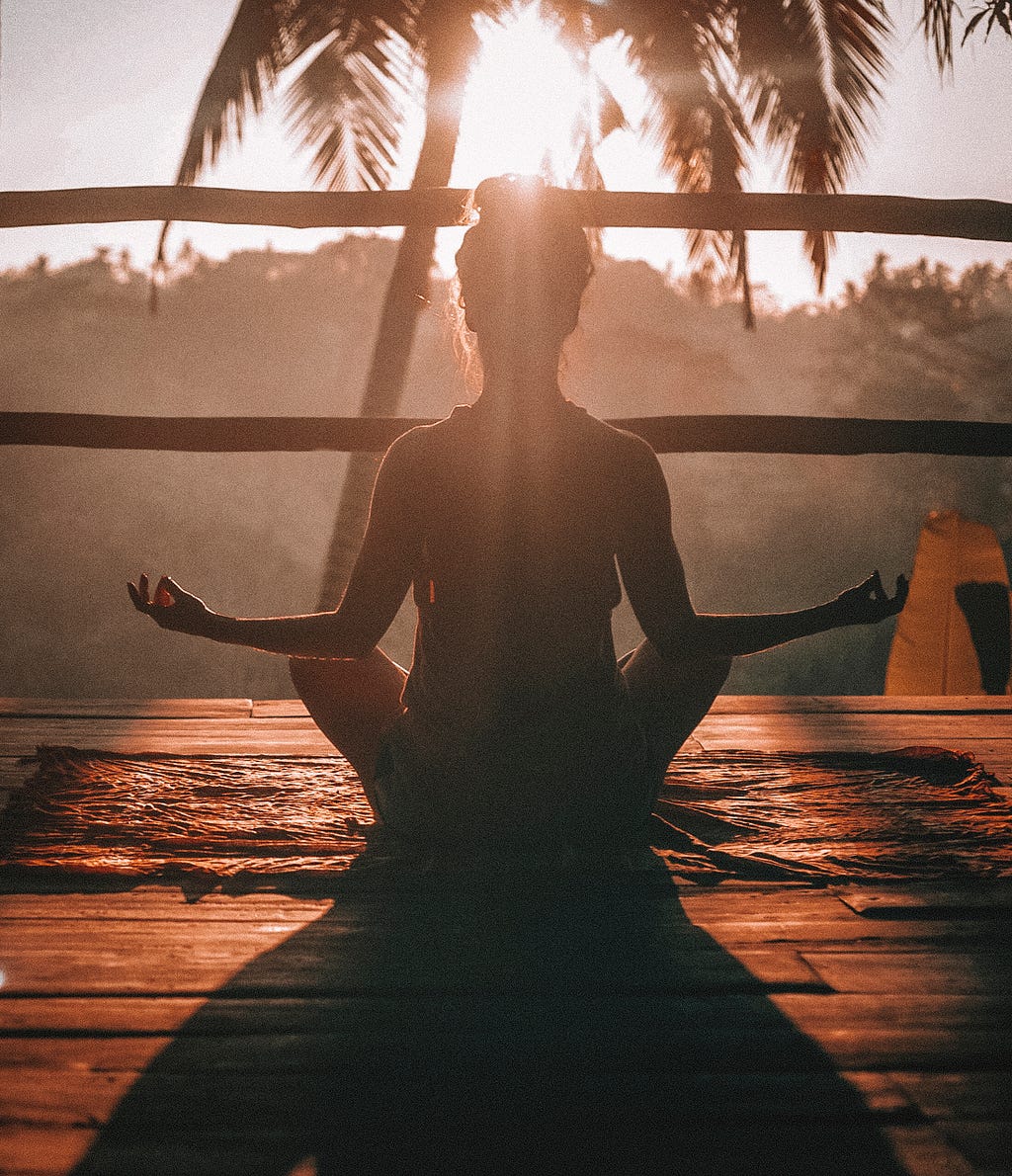 A woman sitting in meditation at sunrise.