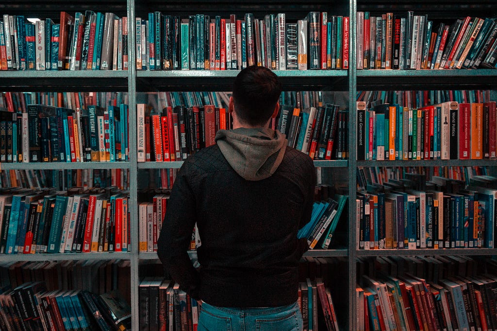 A man looks at a bookcase in a library