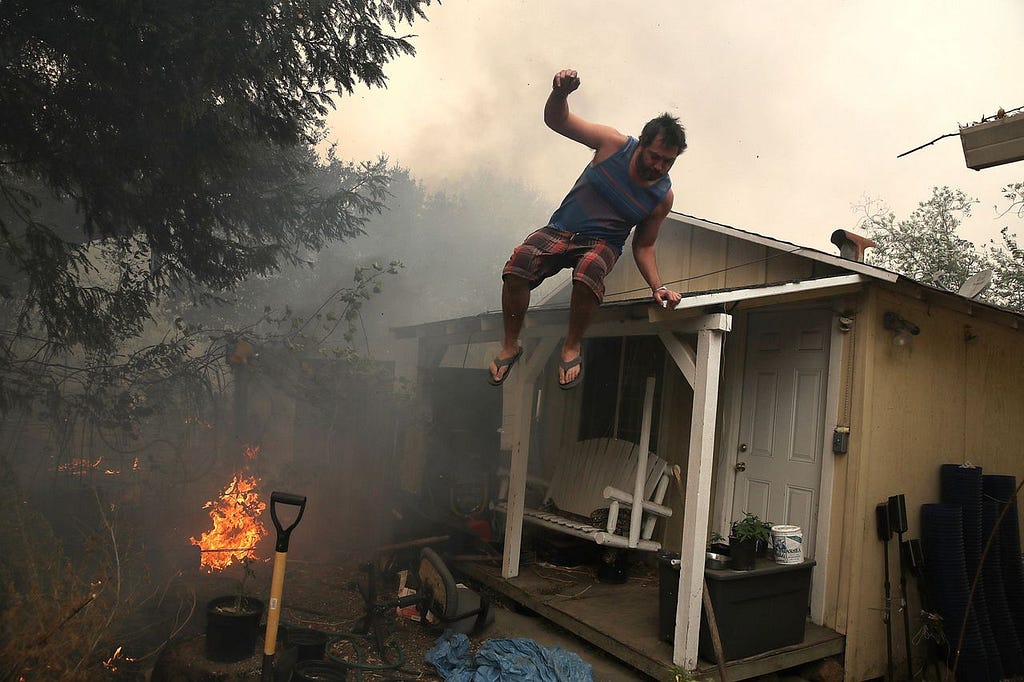 GLEN ELLEN, CA - OCTOBER 09: A resident rushes to save his home as an out of control wildfire moves through the area on October 9, 2017 in Glen Ellen, California. Tens of thousands of acres and dozens of homes and businesses have burned in widespread wildfires that are burning in Napa and Sonoma counties. (Photo by Justin Sullivan/Getty Images)